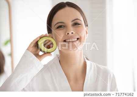 Active young lady posing with half of avocado in hand 71774162