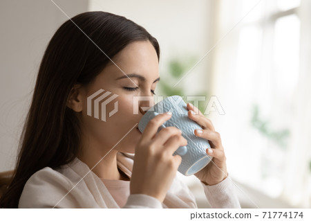 Happy young woman having great pleasure drinking aromatic coffee tea Happy young woman having great pleasure drinking aromatic coffee tea 71774174