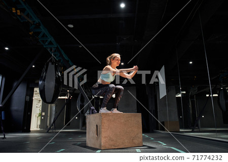 Woman jumping at a crossfit style Woman jumping at a crossfit style 71774232