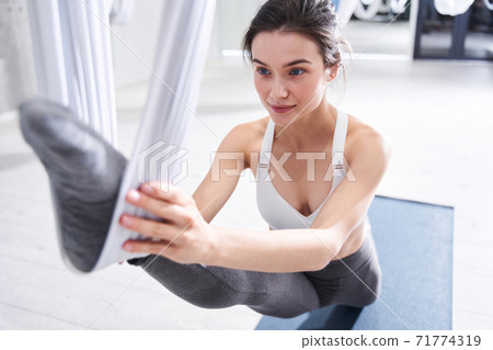 Woman doing aerial yoga practice in hammock Woman doing aerial yoga practice in hammock 71774319