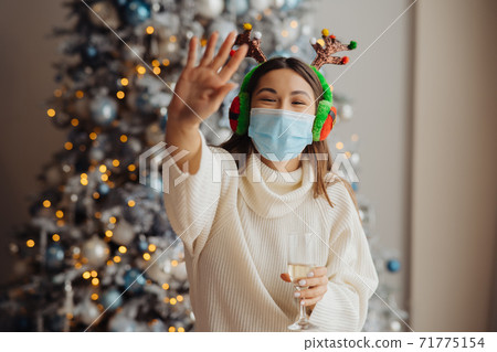 Beautiful young woman in protective mask with glass of champagne 71775154