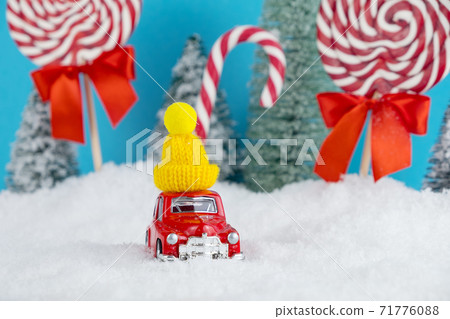 Red Santa car with in yellow winter cap and Christmas tree forest with candies and lollipops sweets. Merry Christmas and Happy New Year Red Santa car with in yellow winter cap and Christmas tree forest with candies and lollipops sweets. Merry Christmas and Happy New Year 71776088