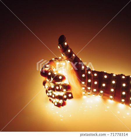 thumbs up hand covered with warm yellow led lights, illuminated background 71778314