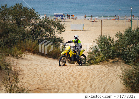 off-road motorcycle enduro motocross rider on sand dune, sea beach background 71778322