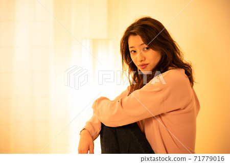 一個女人在晚上在客廳裡放鬆 一個女人在晚上在客廳裡放鬆 71779016