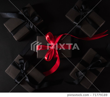 gift box wrapped black paper and black bow ribbon present around the box with a red ribbon 71779189