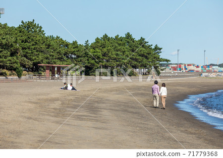 Parents and children lying down with a couple taking a walk in a sunny beach park Parents and children lying down with a couple taking a walk in a sunny beach park 71779368