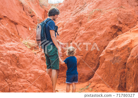 Father and son travelers in red canyon near Mui Ne, southern Vietnam. Traveling with children concept Father and son travelers in red canyon near Mui Ne, southern Vietnam. Traveling with children concept 71780327