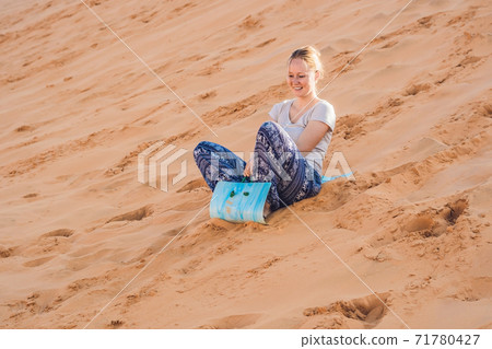 Young woman rolls on a toboggan in the sledge in the desert Young woman rolls on a toboggan in the sledge in the desert 71780427
