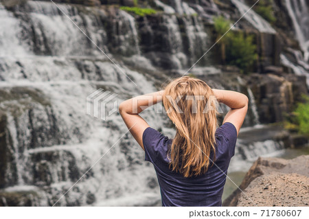 Young woman hiker, tourist on the background of Amazing Pongour Waterfall is famous and most beautiful of fall in Vietnam. Not far from Dalat city estimate 45 Km. Dalat, Vietnam Young woman hiker, tourist on the background of Amazing Pongour Waterfall is famous and most beautiful of fall in Vietnam. Not far from Dalat city estimate 45 Km. Dalat, Vietnam 71780607