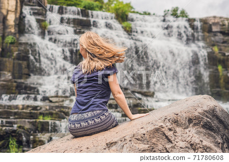 Young woman hiker, tourist on the background of Amazing Pongour Waterfall is famous and most beautiful of fall in Vietnam. Not far from Dalat city estimate 45 Km. Dalat, Vietnam Young woman hiker, tourist on the background of Amazing Pongour Waterfall is famous and most beautiful of fall in Vietnam. Not far from Dalat city estimate 45 Km. Dalat, Vietnam 71780608