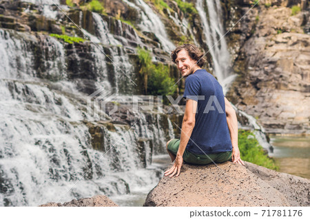 Man hiker, tourist on the background of Amazing Pongour Waterfall is famous and most beautiful of fall in Vietnam. Not far from Dalat city estimate 45 Km. Dalat, Vietnam 71781176