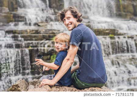 Father and son hikers, tourists on the background of Amazing Pongour Waterfall is famous and most beautiful of fall in Vietnam. Not far from Dalat city estimate 45 Km. Dalat, Vietnam 71781178