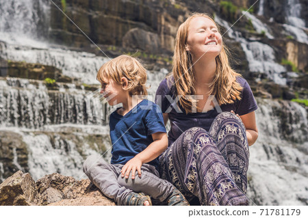 Mother and son hikers, tourists on the background of Amazing Pongour Waterfall is famous and most beautiful of fall in Vietnam. Not far from Dalat city estimate 45 Km. Dalat, Vietnam Mother and son hikers, tourists on the background of Amazing Pongour Waterfall is famous and most beautiful of fall in Vietnam. Not far from Dalat city estimate 45 Km. Dalat, Vietnam 71781179