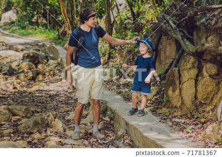 Father and son are walking along the forest road 71781367
