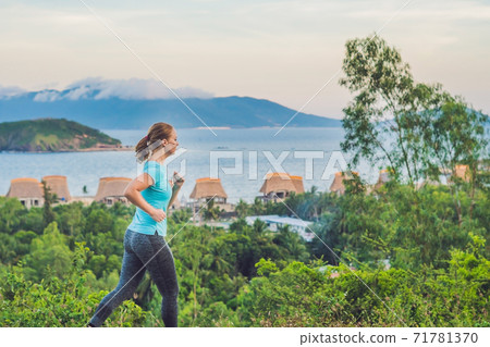 A sportive young woman is engaged in running against the sea A sportive young woman is engaged in running against the sea 71781370