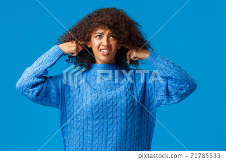 Bothered and interrupted displeased african-american college student female in winter sweater, looking up and grimacing, shut ears with fingers, not hear loud awful music, neigbours having party 71785533