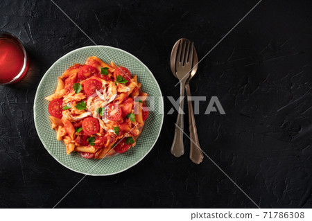 Penne pasta with pulled chicken, tomato sauce and fresh parsley leaves, shot from the top on a dark background Penne pasta with pulled chicken, tomato sauce and fresh parsley leaves, shot from the top on a dark background 71786308