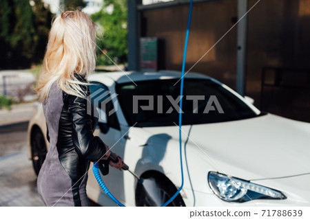 Beautiful blonde woman washes car foam at car wash 71788639