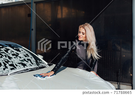 Beautiful blonde woman washes car foam at car wash Beautiful blonde woman washes car foam at car wash 71788665