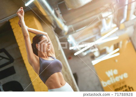 Young attractive fitness woman in sportswear with perfect body doing stretching exercises, warming up before workout at gym Young attractive fitness woman in sportswear with perfect body doing stretching exercises, warming up before workout at gym 71788928