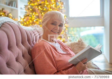 Senior woman reading a book and smiling nicely Senior woman reading a book and smiling nicely 71789969