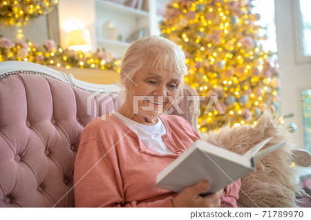 Senior woman reading a book and smiling Senior woman reading a book and smiling 71789970