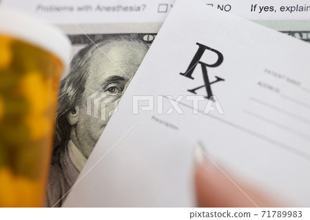 Dollar bill and doctors prescription are on doctors table in clinic closeup Dollar bill and doctors prescription are on doctors table in clinic closeup 71789983