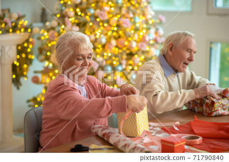 Elderly couple packing christmas gifts and feeling enjoyed Elderly couple packing christmas gifts and feeling enjoyed 71790840