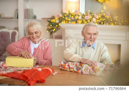 Elderly couple packing christmas gifts and looking involved 71790864