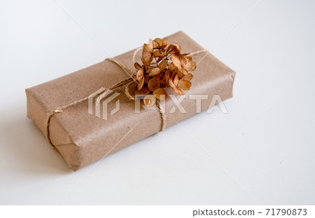 Gift box wrapped in craft paper with natural rustic rope on a white background with dried hydrangea flowers 71790873