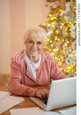 Elderly woman working on a laptop and smiling 71790899