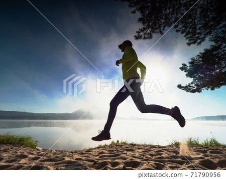 Tall slim runner on sandy beay along lake. Healthy style Tall slim runner on sandy beay along lake. Healthy style 71790956