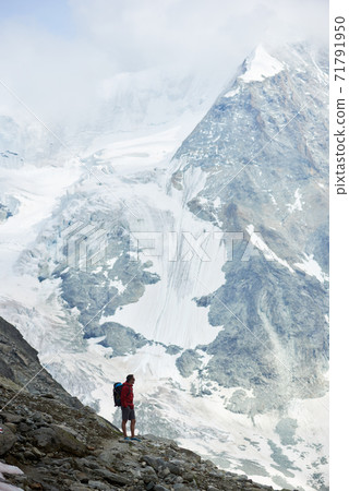 Male tourist climbing snowy rocky cliffs of beautiful Penning Alps in Switzerland Male tourist climbing snowy rocky cliffs of beautiful Penning Alps in Switzerland 71791950