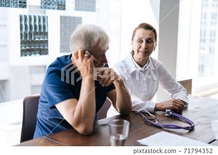 Professional doctor and nurse examining together history disease of patient using MRI scan of head Professional doctor and nurse examining together history disease of patient using MRI scan of head 71794352