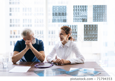 Medical team of doctors discussing history disease of patient using MRI scan of head. Medical team of doctors discussing history disease of patient using MRI scan of head. 71794353