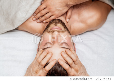 Man receiving head massage. 71795435