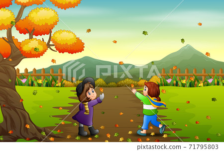 Happy girls catching falling leaf in autumn landscape 71795803