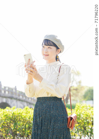 一個女人在旅遊區的智能手機 71796220