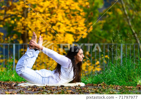 Yoga position by a young woman in the park in autumn Yoga position by a young woman in the park in autumn 71797977