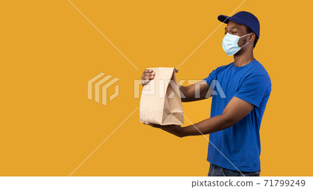 Black delivery man in medical face mask holding package Black delivery man in medical face mask holding package 71799249