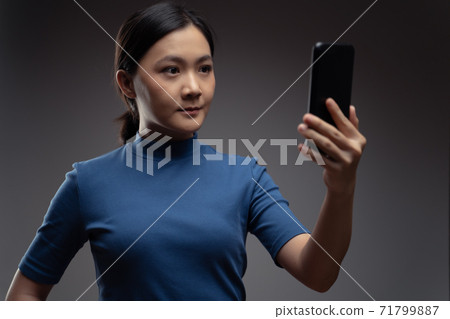 Asian woman scans face by smart phone using facial recognition system. Asian woman scans face by smart phone using facial recognition system. 71799887