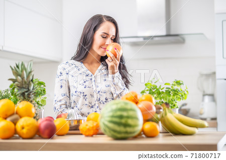 Woman in the kitchen enjoying the aroma of fresh grapefruit Woman in the kitchen enjoying the aroma of fresh grapefruit 71800717