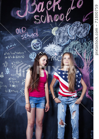 back to school after summer vacations, two teen real girls in classroom with blackboard painted together, lifestyle people concept 71800759