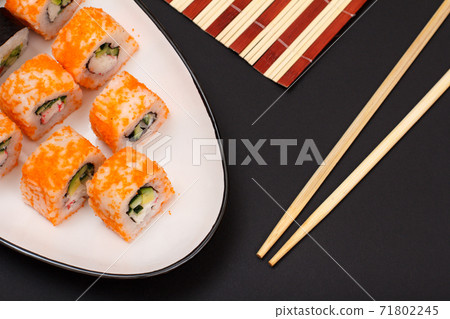 Uramaki California. Sushi rolls, wooden napkin and sticks on black background. Uramaki California. Sushi rolls, wooden napkin and sticks on black background. 71802245