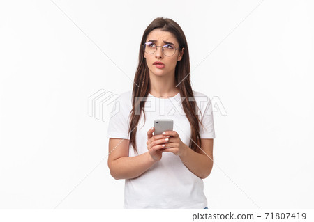 Communication, technology and lifestyle concept. Portrait of troubled and concerned young woman worried for friend, sending text message if shes okay and thinking, look up nervous, hold mobile phone 71807419