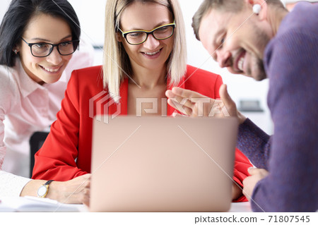 Two women and man waving to other at laptop screen in office 71807545