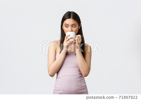 Lifestyle, people emotions and glamour concept. Thoughtful sensual asian woman in evening dress, looking away thinking and drinking coffee from mug, standing white background Lifestyle, people emotions and glamour concept. Thoughtful sensual asian woman in evening dress, looking away thinking and drinking coffee from mug, standing white background 71807822