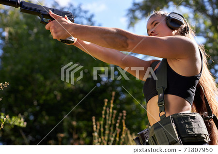 beautiful female in camouflage in her arms during a war is aiming at a target or an enemy, in forest beautiful female in camouflage in her arms during a war is aiming at a target or an enemy, in forest 71807950