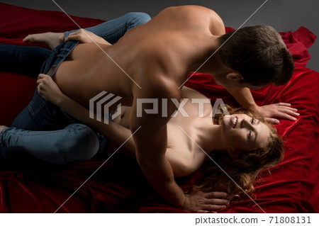 Passionate couple having sex on red sheets 71808131